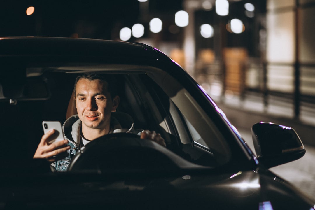 young-man-driving-his-car-night-time-talking-phone