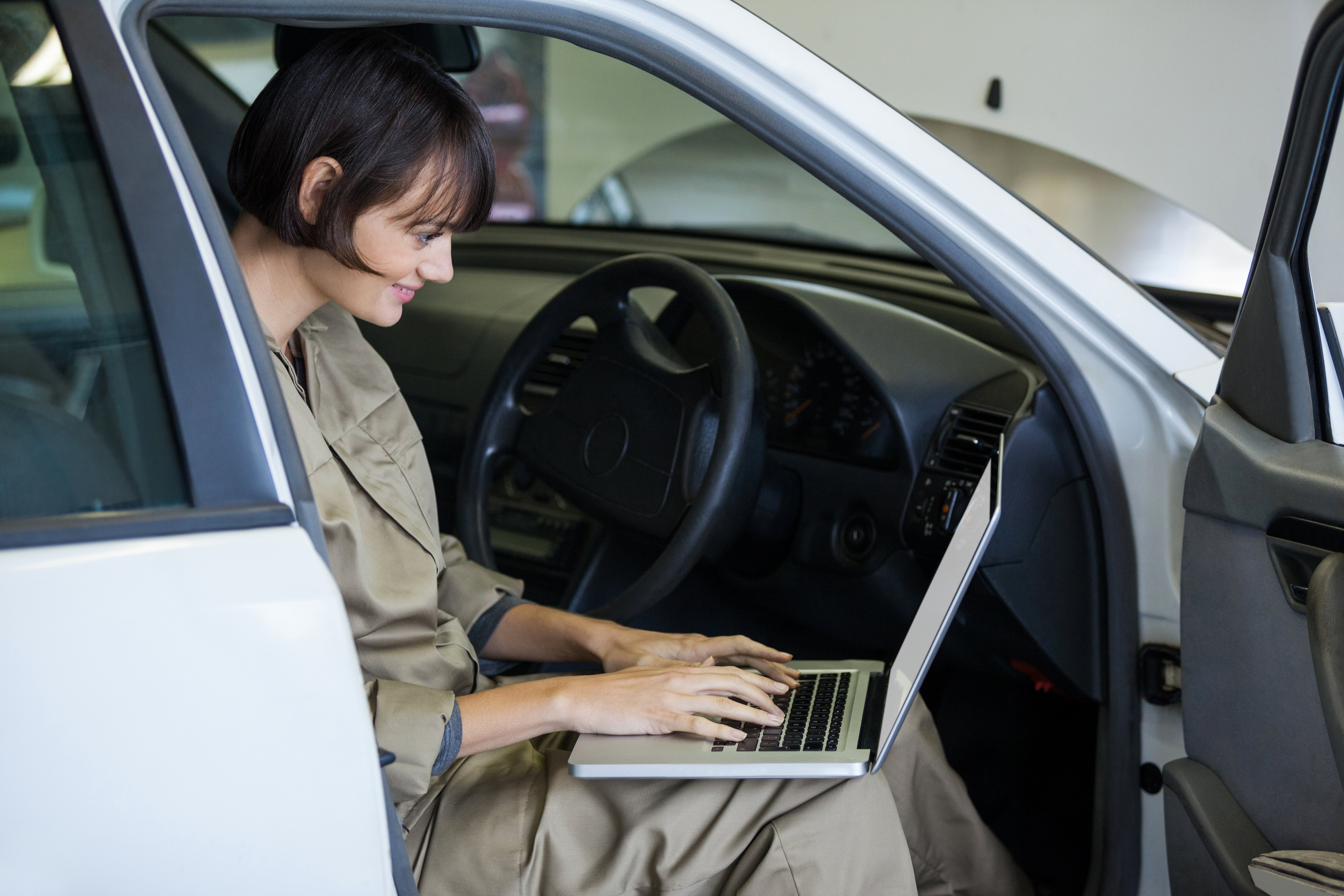 smiling-female-mechanic-using-laptop