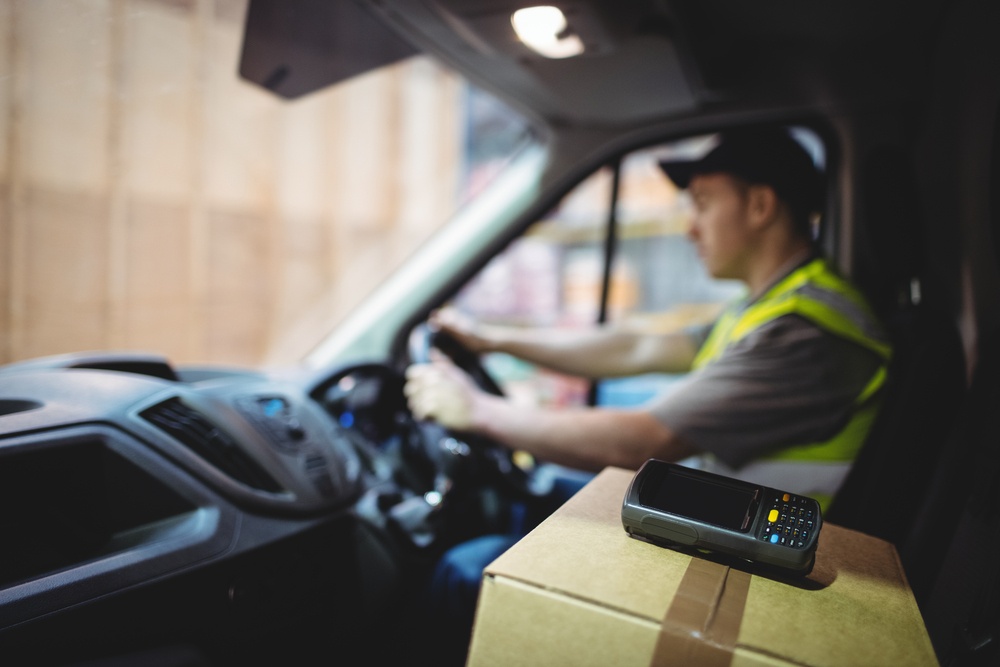 Delivery driver driving van with parcels on seat outside warehouse-5