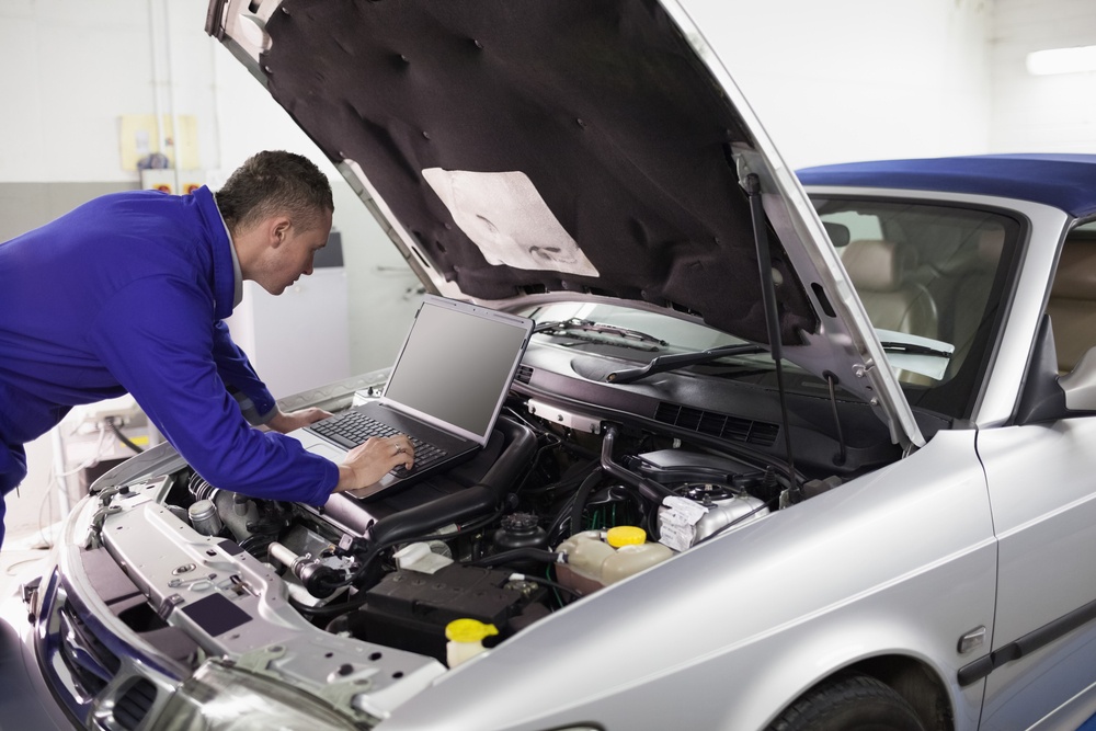 Mechanic typing on a computer while looking it in a garage